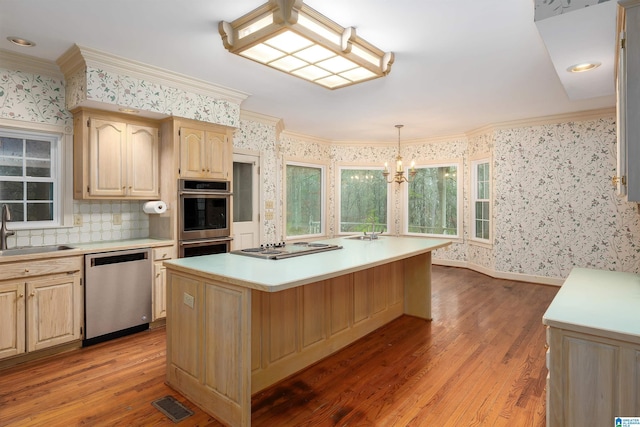 kitchen featuring appliances with stainless steel finishes, pendant lighting, sink, a center island, and crown molding