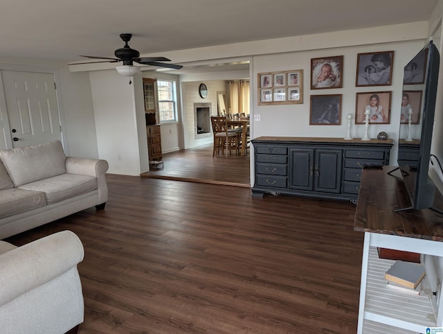 living room featuring a brick fireplace, dark hardwood / wood-style floors, and ceiling fan