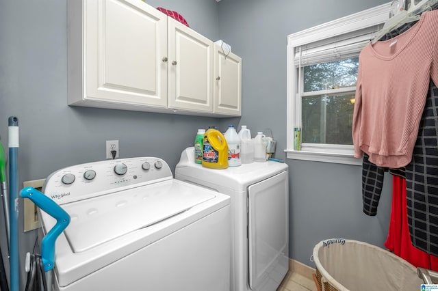 clothes washing area with cabinets and washer and dryer