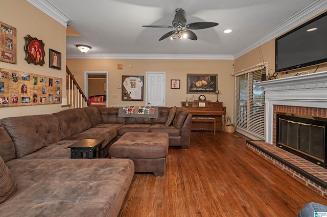 living room featuring crown molding, ceiling fan, a brick fireplace, and hardwood / wood-style flooring