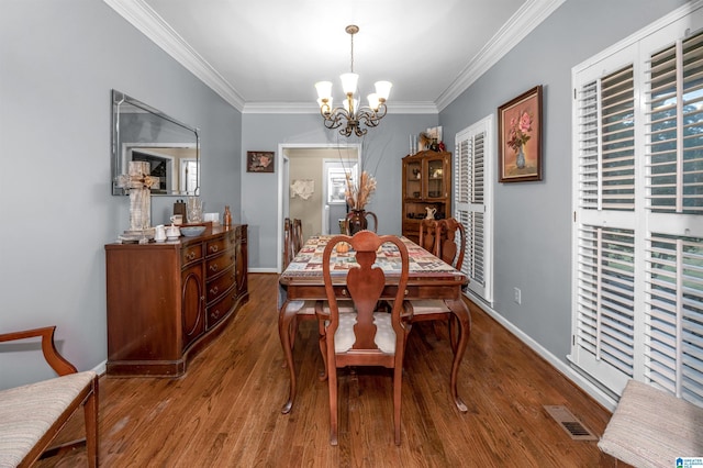 dining room featuring wood-type flooring, ornamental molding, and a chandelier