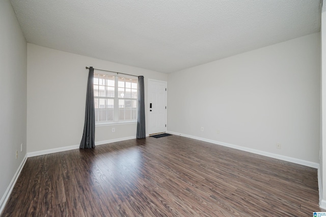 unfurnished room with dark wood-type flooring and a textured ceiling