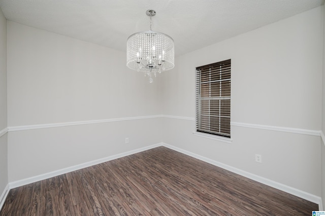 unfurnished room with dark hardwood / wood-style flooring, a textured ceiling, and an inviting chandelier