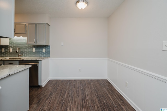 kitchen with sink, dark wood-type flooring, dishwasher, gray cabinetry, and backsplash