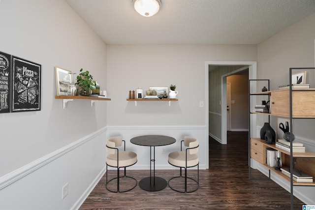 dining room featuring dark wood-type flooring and a textured ceiling