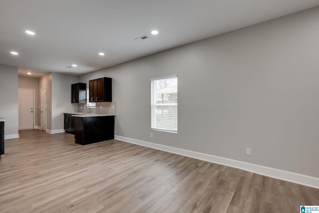 kitchen with dark brown cabinetry, sink, and light wood-type flooring