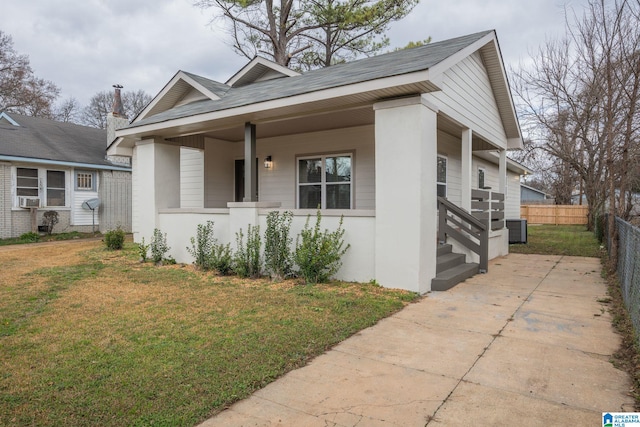 bungalow featuring a porch, cooling unit, central AC unit, and a front lawn