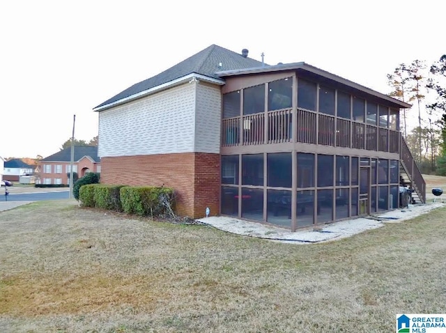 view of side of home with a sunroom, stairs, a lawn, and brick siding