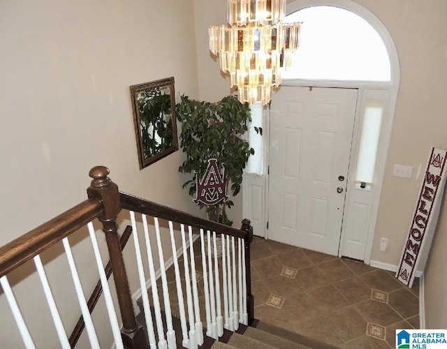 entryway with dark tile patterned floors and an inviting chandelier