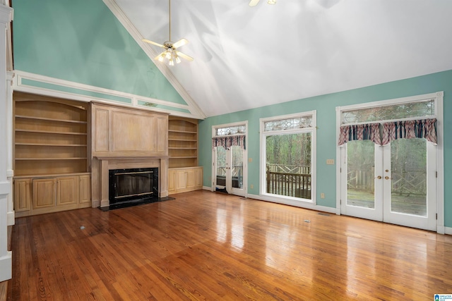 unfurnished living room with ceiling fan, wood-type flooring, high vaulted ceiling, and french doors