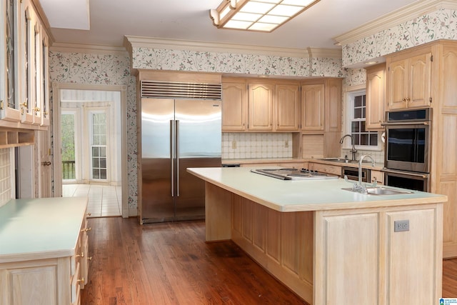 kitchen featuring ornamental molding, appliances with stainless steel finishes, a kitchen island with sink, and sink