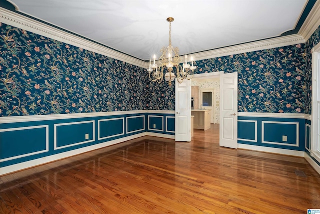 unfurnished room with a notable chandelier, hardwood / wood-style flooring, and ornamental molding