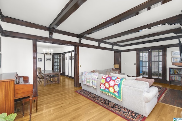 living room featuring french doors, beamed ceiling, hardwood / wood-style flooring, and a notable chandelier