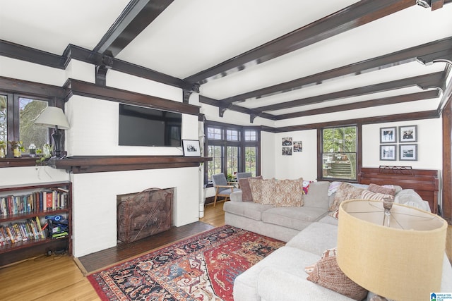 living room featuring beamed ceiling, a healthy amount of sunlight, hardwood / wood-style floors, and a fireplace