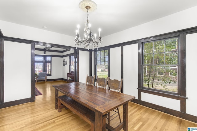 dining room featuring beam ceiling, a chandelier, and light hardwood / wood-style flooring