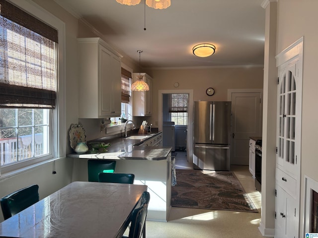 kitchen with pendant lighting, a wealth of natural light, white cabinetry, sink, and stainless steel appliances