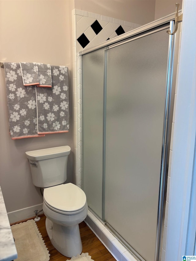 bathroom with wood-type flooring, a shower with door, and toilet