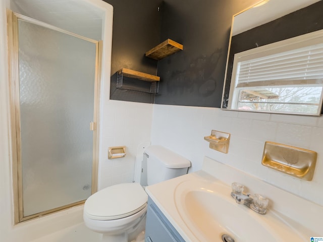 bathroom featuring a shower with door, vanity, tile walls, and toilet