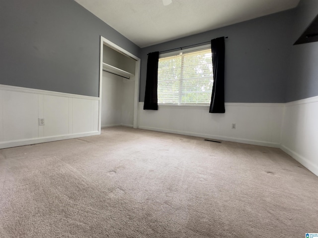 unfurnished bedroom with a closet, light carpet, and a textured ceiling