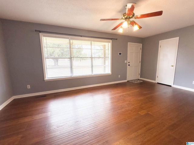 spare room featuring a healthy amount of sunlight, dark hardwood / wood-style floors, a textured ceiling, and ceiling fan