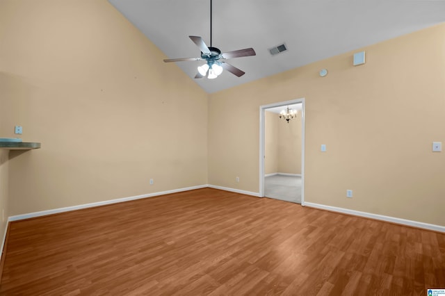 empty room with hardwood / wood-style floors, ceiling fan with notable chandelier, and high vaulted ceiling