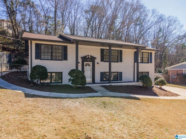 raised ranch with a front yard and brick siding