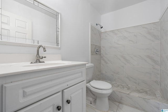 bathroom featuring vanity, a tile shower, and toilet