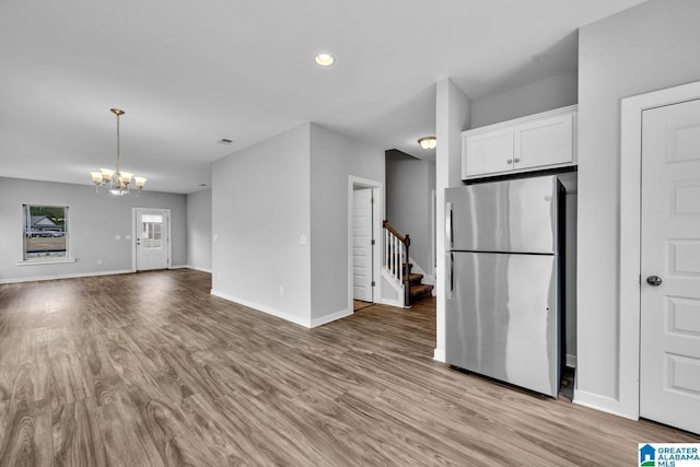 kitchen with a notable chandelier, white cabinetry, stainless steel fridge, and light wood-type flooring