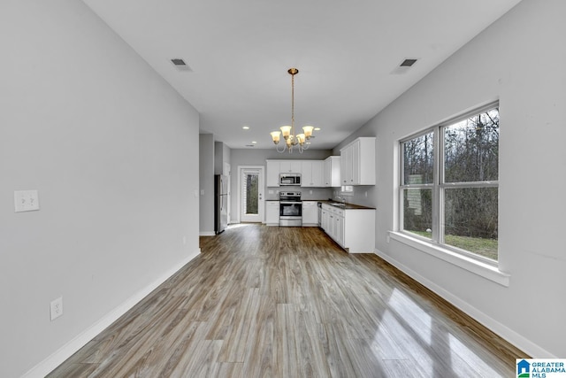 unfurnished living room featuring a chandelier, sink, and light wood-type flooring