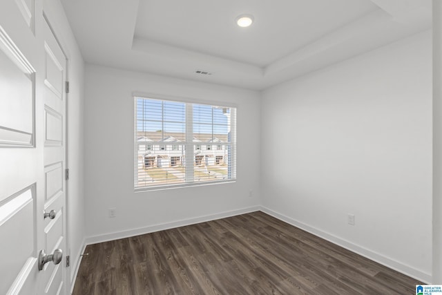 unfurnished bedroom with dark hardwood / wood-style floors and a tray ceiling