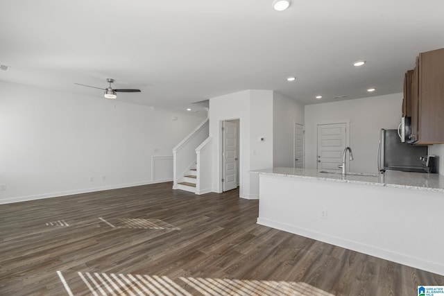 kitchen with ceiling fan, dark hardwood / wood-style flooring, light stone countertops, and sink