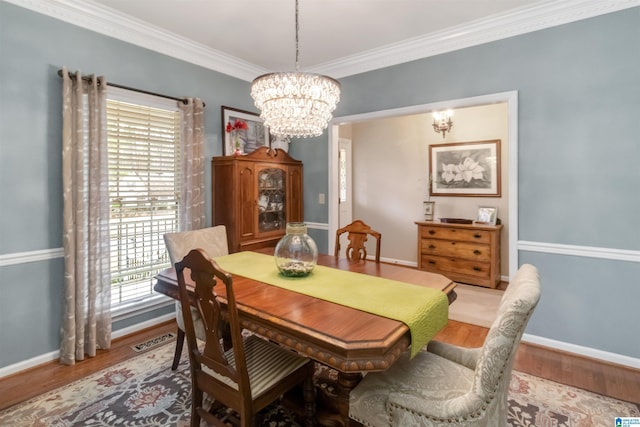 dining area featuring an inviting chandelier, wood-type flooring, and crown molding