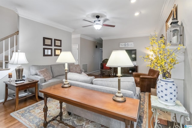 living room with wood-type flooring, ceiling fan, and crown molding