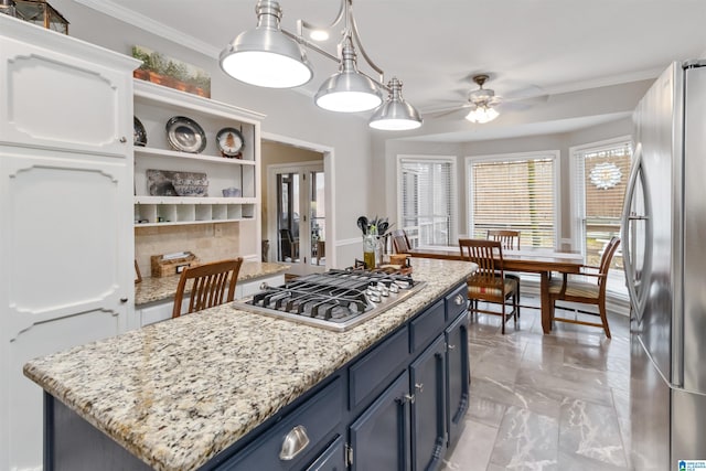 kitchen featuring a kitchen island, appliances with stainless steel finishes, blue cabinets, white cabinets, and crown molding