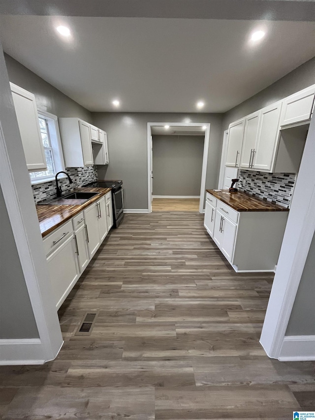 kitchen with white cabinets, hardwood / wood-style flooring, sink, and wooden counters