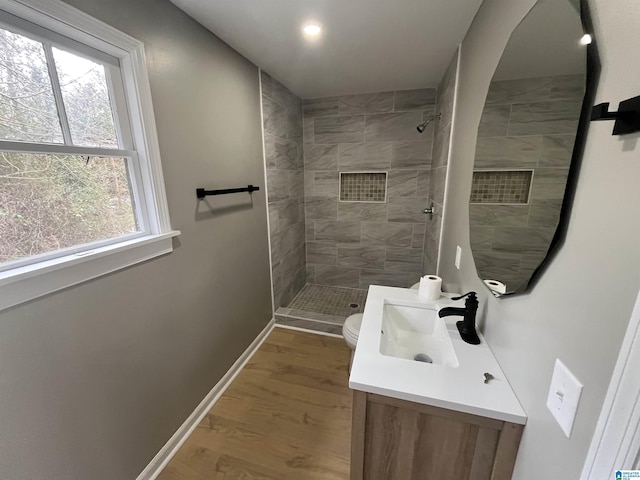 bathroom with vanity, hardwood / wood-style flooring, toilet, and tiled shower