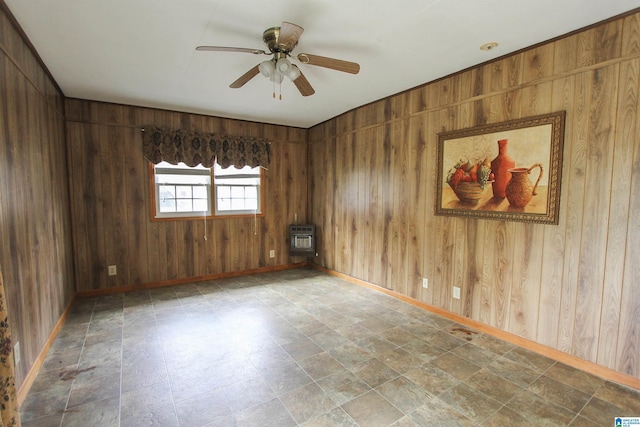 empty room featuring ceiling fan, wooden walls, and heating unit