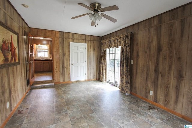 spare room featuring ceiling fan, a wealth of natural light, and wooden walls