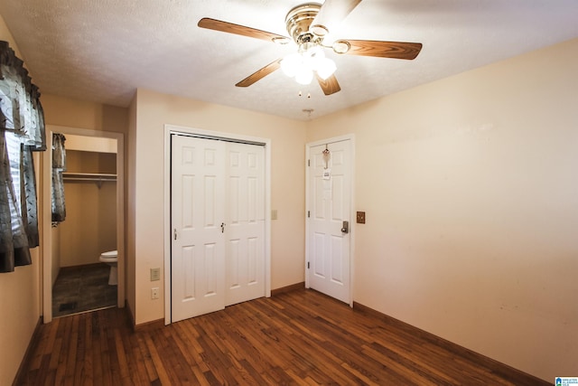 unfurnished bedroom featuring dark hardwood / wood-style flooring, a textured ceiling, and ceiling fan