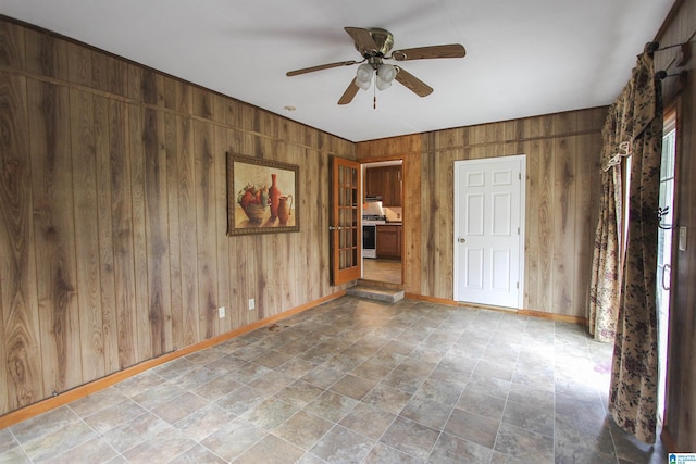 spare room featuring ceiling fan and wood walls