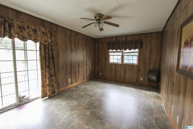 spare room with ceiling fan, heating unit, and wooden walls