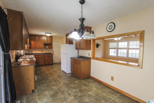 kitchen featuring pendant lighting, sink, white fridge, and a notable chandelier