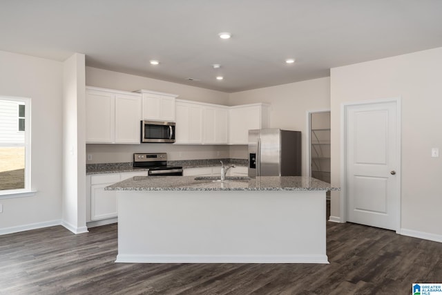 kitchen featuring appliances with stainless steel finishes, white cabinetry, a kitchen island with sink, dark hardwood / wood-style floors, and light stone countertops