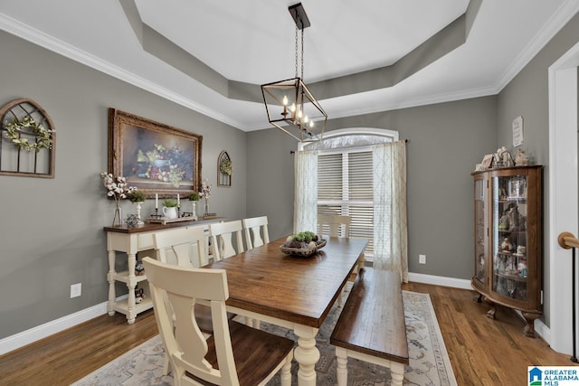 dining room featuring wood-type flooring, crown molding, and a tray ceiling