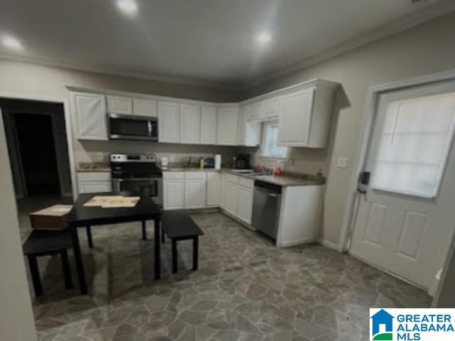 kitchen with ornamental molding, stainless steel appliances, and white cabinets