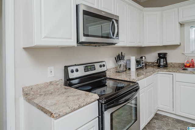 kitchen with sink, light stone countertops, white cabinets, and appliances with stainless steel finishes