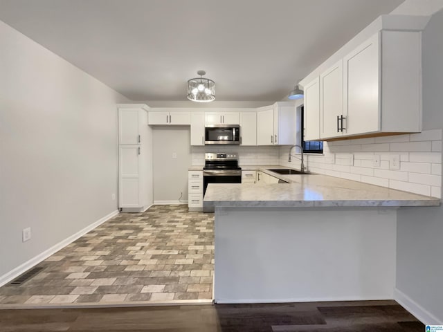 kitchen featuring sink, white cabinetry, kitchen peninsula, stainless steel appliances, and decorative backsplash