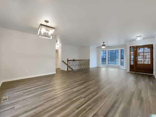 unfurnished living room featuring ceiling fan with notable chandelier and dark hardwood / wood-style floors