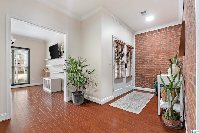 foyer entrance with brick wall, wood-type flooring, and ornamental molding