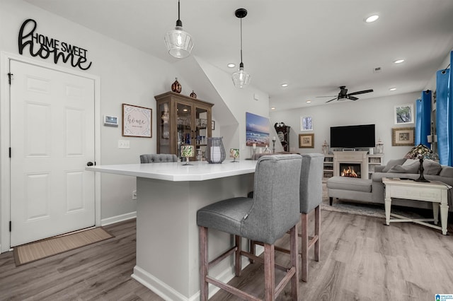 kitchen with pendant lighting, a kitchen bar, a center island, and light hardwood / wood-style flooring